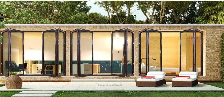 Pool house aux fenêtres en accordéon repliées, ouvert sur la terrasse et ses bains de soleil