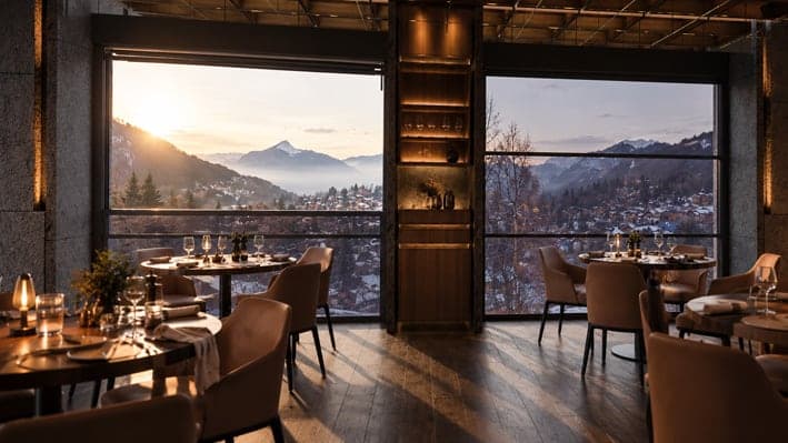 Salle de restaurant en montagne derrière de grandes fenêtres guillotine, coucher de soleil sur les sommets