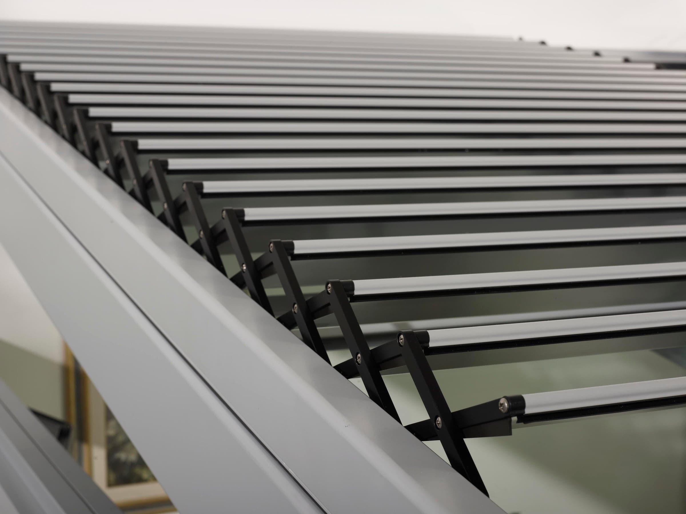 Lames aluminium orientables entrouvertes au-dessus d’une verrière