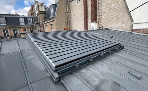 Lames Obskura fermées sur une verrière, au milieu des toits de Paris