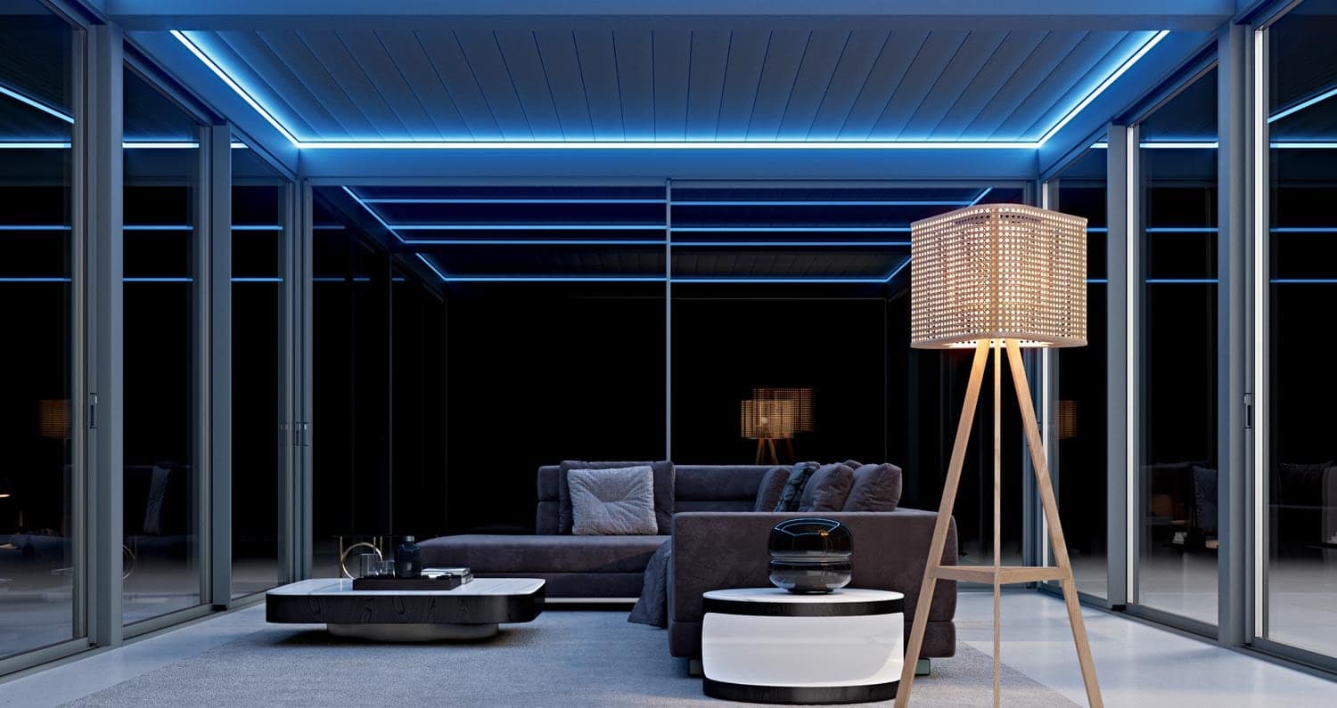 Pergola fermée de baies vitrées, plafond à lames souligné de LED bleues, salon éclairé de nuit
