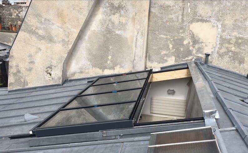 Vantail vitré escamoté dans un toit en zinc, ouverture dégagée sur la pièce en dessous