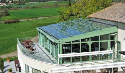 Véranda aluminium à toiture vitrée sur la terrasse d’un restaurant, face à la campagne