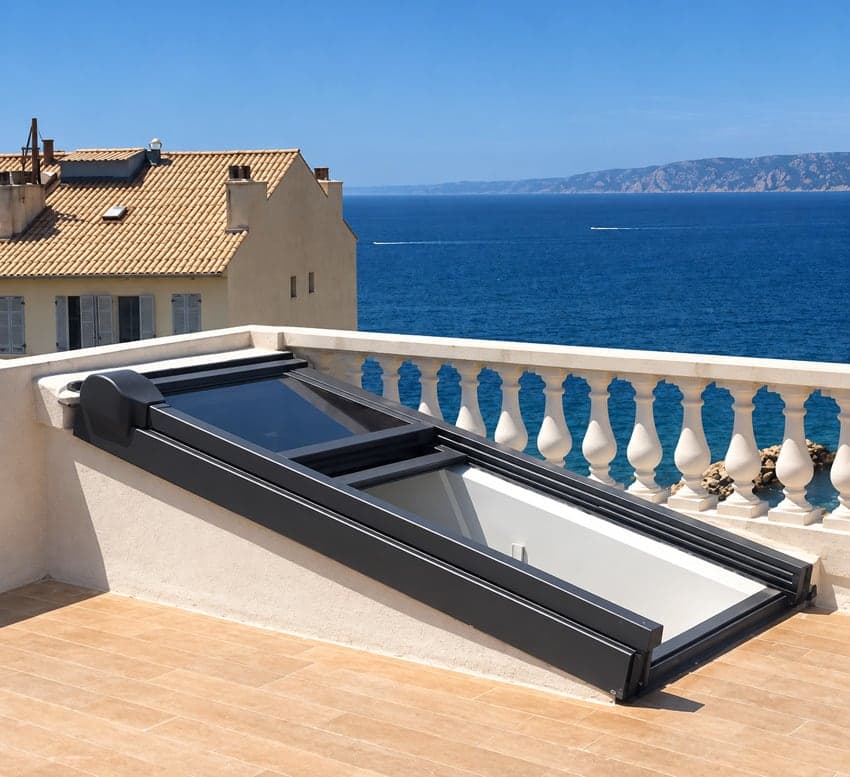 Accès vitré coulissant entrouvert sur un toit-terrasse à balustres, face à la mer à Marseille