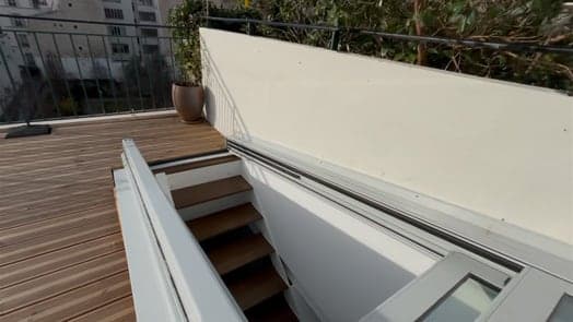 Accès de toit-terrasse ouvert sur une terrasse en bois, marches de l’escalier visibles